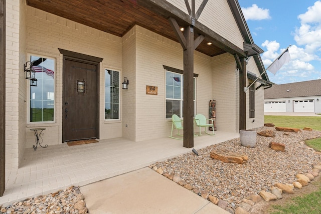 doorway to property featuring covered porch and brick siding