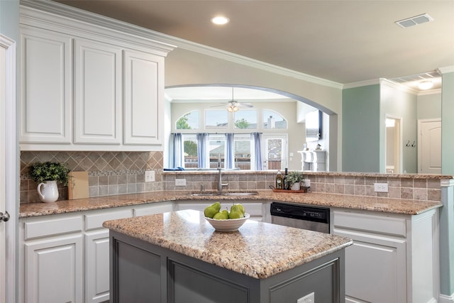 kitchen with stainless steel dishwasher, visible vents, a kitchen island, white cabinets, and a sink