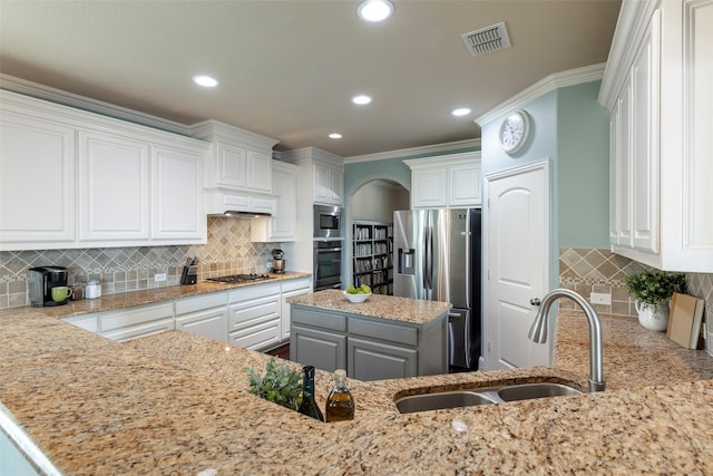 kitchen featuring a sink, light stone counters, tasteful backsplash, and stainless steel appliances