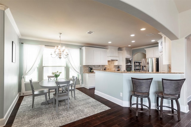 kitchen with crown molding, arched walkways, dark wood finished floors, and stainless steel appliances