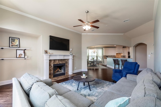 living room with visible vents, arched walkways, dark wood-type flooring, and a ceiling fan