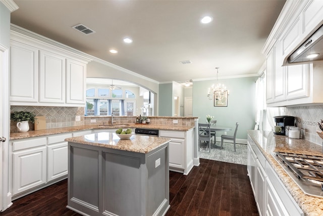 kitchen with visible vents, a center island, a peninsula, stainless steel gas stovetop, and extractor fan