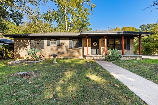 ranch-style house featuring a porch, a front yard, and brick siding