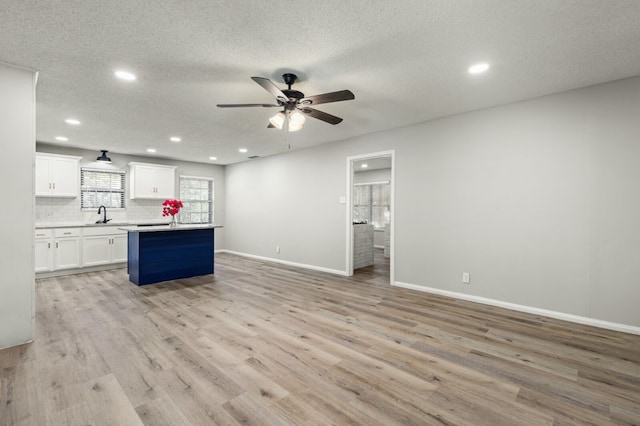 kitchen with white cabinets, ceiling fan, recessed lighting, backsplash, and a kitchen island