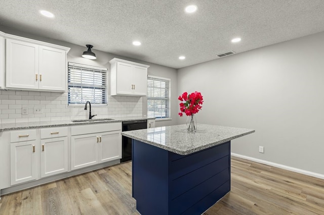 kitchen with visible vents, tasteful backsplash, dishwasher, a sink, and white cabinetry