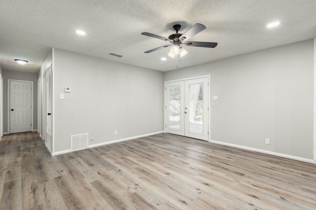 spare room with ceiling fan, french doors, visible vents, wood finished floors, and baseboards