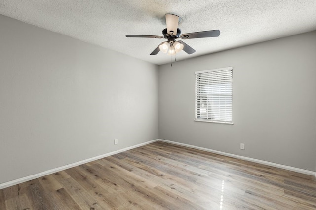 spare room featuring baseboards, a textured ceiling, ceiling fan, and wood finished floors