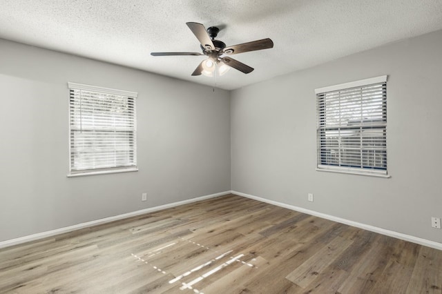 unfurnished room featuring a ceiling fan, a textured ceiling, wood finished floors, and a healthy amount of sunlight