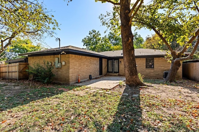 rear view of property featuring brick siding, fence, and a patio