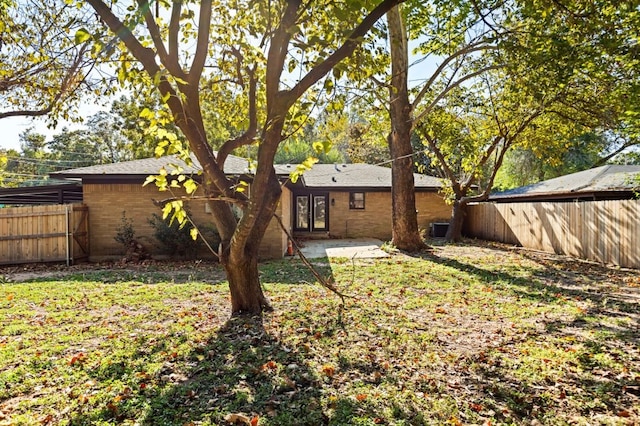 back of property with a lawn, fence, central air condition unit, and brick siding