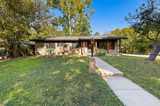 view of front of home with covered porch, brick siding, and a front yard