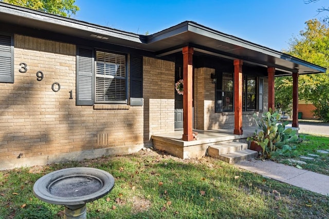 property entrance featuring brick siding and covered porch