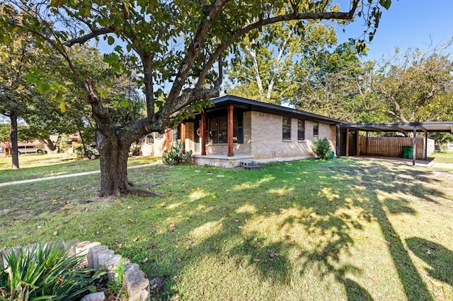 view of home's exterior featuring a lawn, an attached carport, a porch, and brick siding