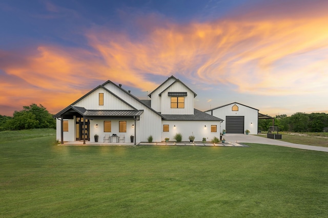 view of front of property with concrete driveway, a standing seam roof, an outdoor structure, a yard, and metal roof