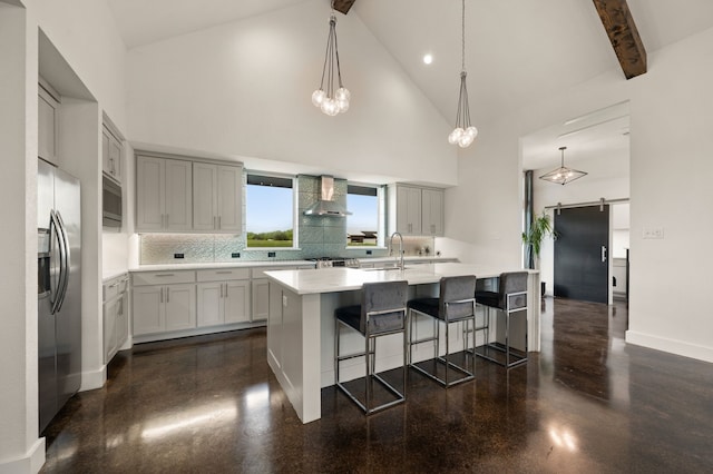 kitchen with wall chimney range hood, appliances with stainless steel finishes, light countertops, high vaulted ceiling, and backsplash