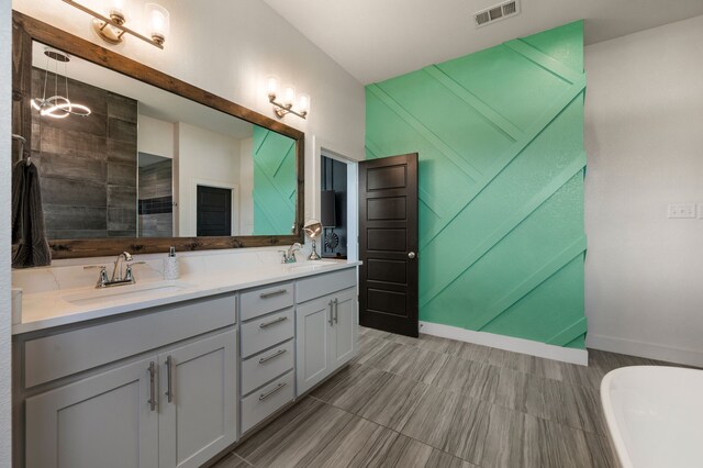 bathroom with visible vents, a sink, double vanity, and a soaking tub