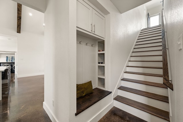 staircase with finished concrete flooring and baseboards