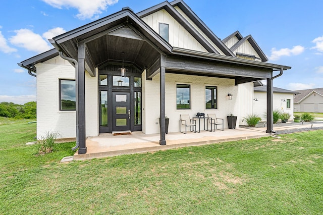 entrance to property featuring board and batten siding, a yard, and brick siding