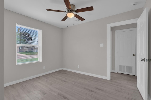 spare room featuring baseboards, ceiling fan, light wood-style flooring, and visible vents
