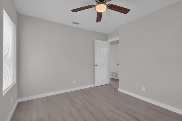 unfurnished room featuring a ceiling fan, visible vents, a healthy amount of sunlight, and wood finished floors