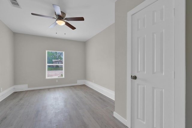 empty room featuring baseboards, ceiling fan, wood finished floors, and visible vents