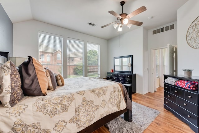 bedroom with a ceiling fan, lofted ceiling, light wood finished floors, and visible vents