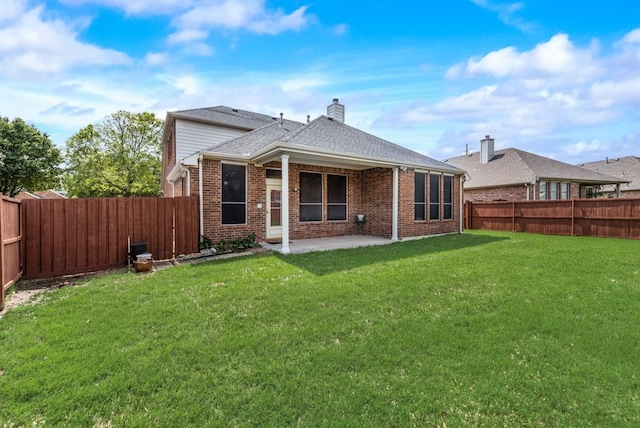 back of property with a fenced backyard, a lawn, a patio area, and brick siding