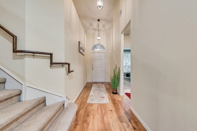 entrance foyer with visible vents, light wood finished floors, baseboards, and stairway