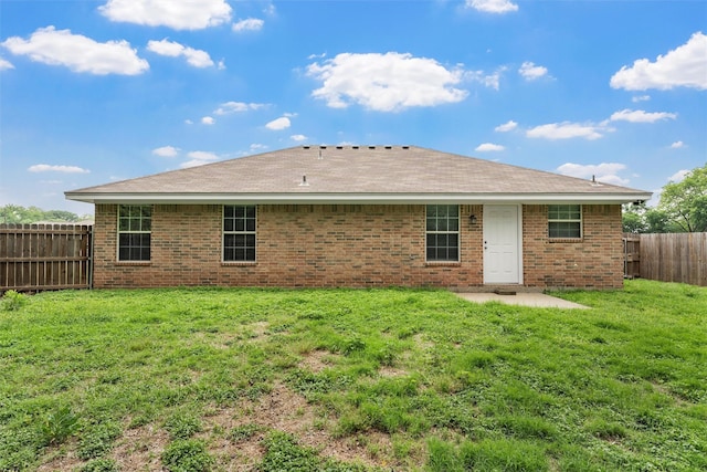 rear view of house with a fenced backyard, a lawn, and brick siding
