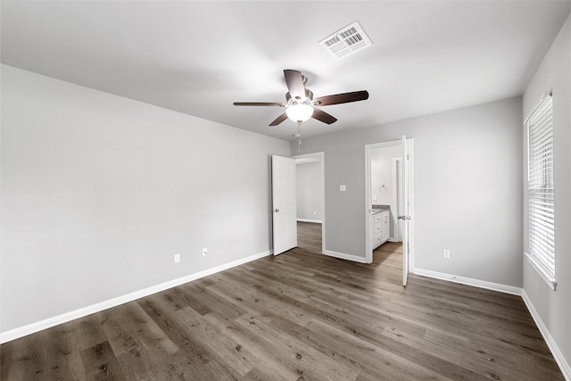 unfurnished bedroom with baseboards, ensuite bathroom, wood finished floors, and visible vents