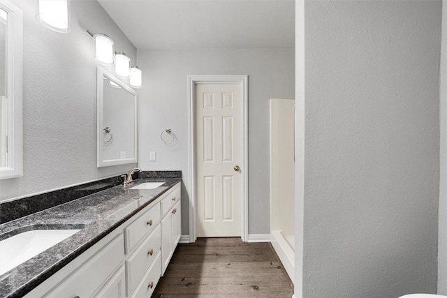 full bath with a walk in shower, double vanity, a sink, and wood finished floors