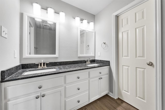 bathroom with double vanity, a sink, wood finished floors, and visible vents