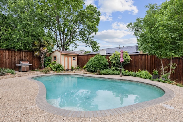 view of pool with a fenced in pool, a fenced backyard, grilling area, and a storage shed