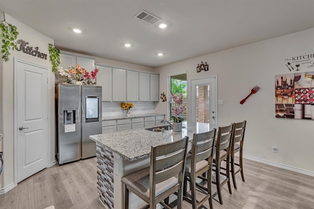 2561 Pettus Dr, Forney, TX 75126 - kitchen with visible vents, a sink, stainless steel fridge with ice dispenser, light stone counters, and light wood-style floors