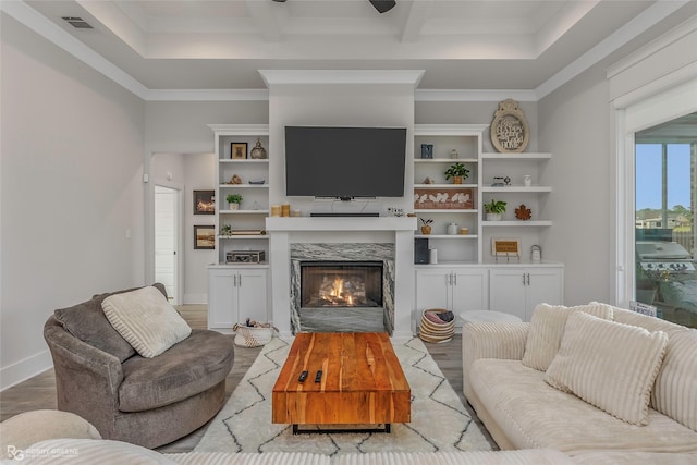 living room featuring visible vents, crown molding, wood finished floors, baseboards, and a premium fireplace