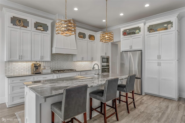 kitchen featuring a breakfast bar area, backsplash, appliances with stainless steel finishes, a sink, and light wood-style floors