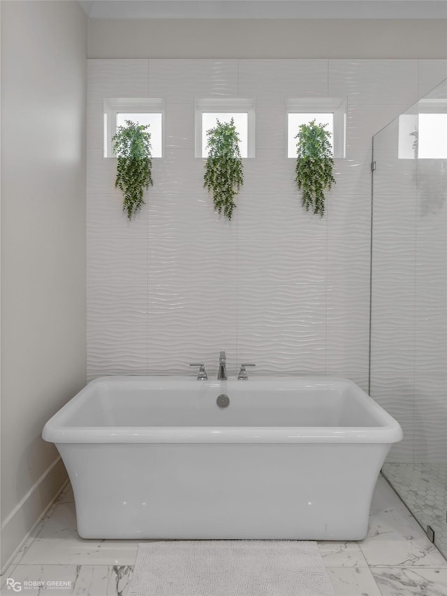 full bath featuring baseboards, marble finish floor, and a freestanding tub