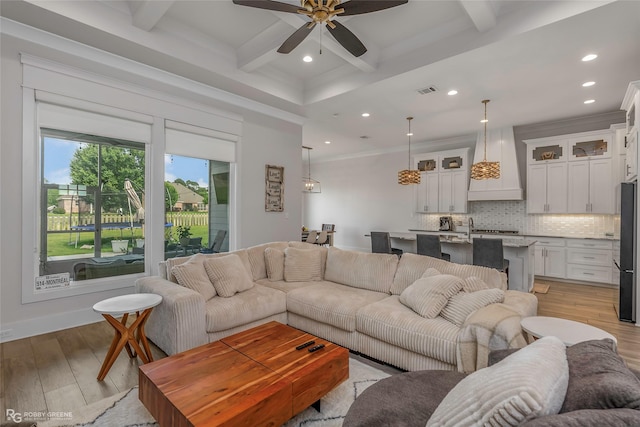 living area featuring light wood-style floors, recessed lighting, ceiling fan, and beamed ceiling