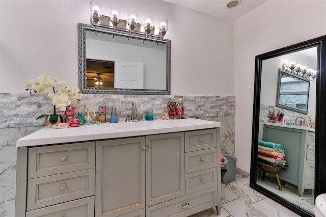 bathroom with tile walls, a wainscoted wall, vanity, and marble finish floor
