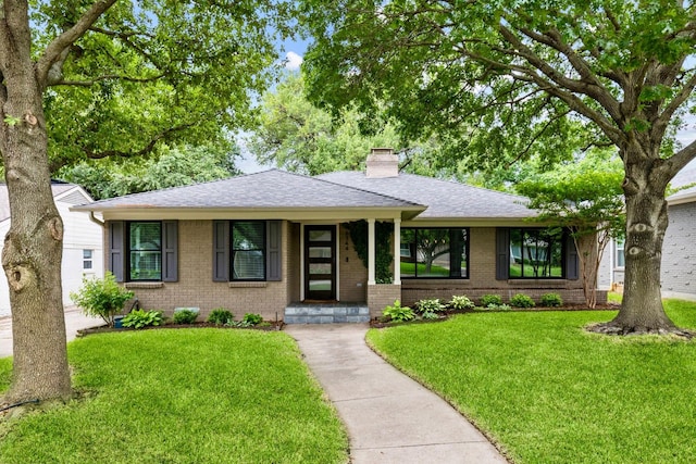 ranch-style house with brick siding, a front lawn, roof with shingles, and a chimney