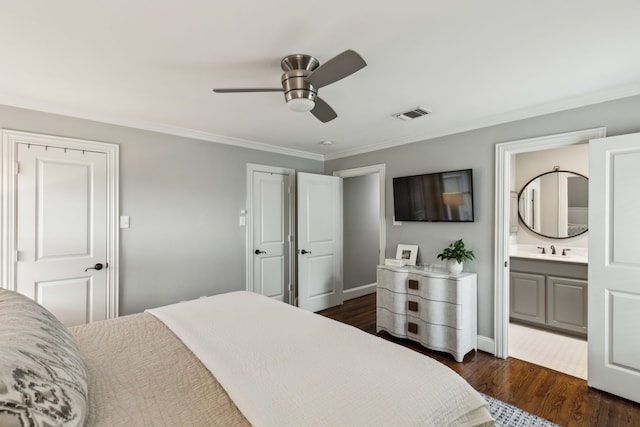 bedroom featuring visible vents, crown molding, dark wood finished floors, a sink, and ensuite bath