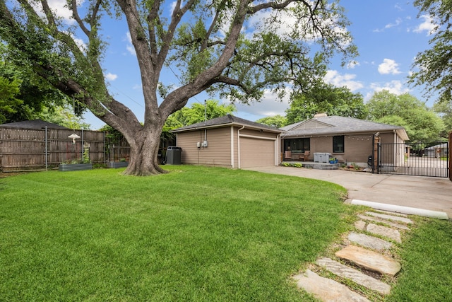view of yard featuring a garage, fence, driveway, and cooling unit