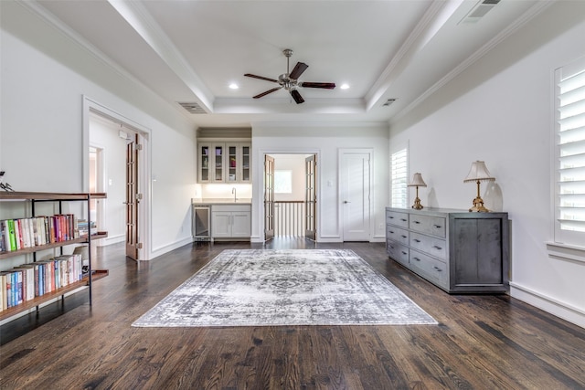 sitting room with a tray ceiling, a ceiling fan, dark wood-type flooring, and visible vents