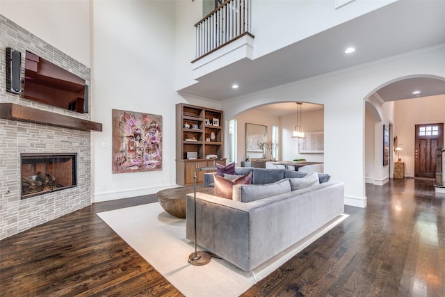 living room with a fireplace, baseboards, ornamental molding, and dark wood-type flooring