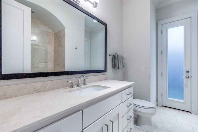 bathroom featuring vanity, ornamental molding, a tile shower, and toilet