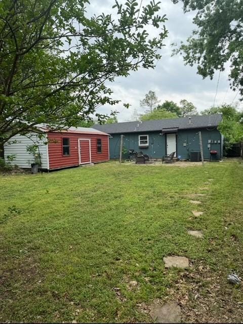 rear view of house featuring a storage unit, an outbuilding, and a yard