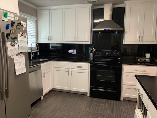 kitchen featuring decorative backsplash, wall chimney range hood, white cabinetry, a sink, and appliances with stainless steel finishes
