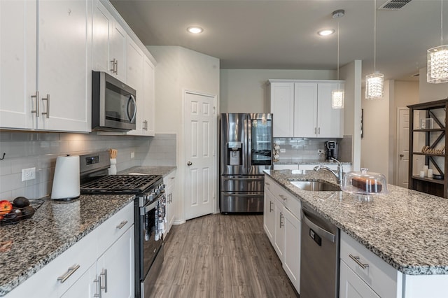 600 Goldenrod Ln, Princeton, TX 75407 - kitchen with white cabinets, appliances with stainless steel finishes, a sink, a kitchen bar, and visible vents