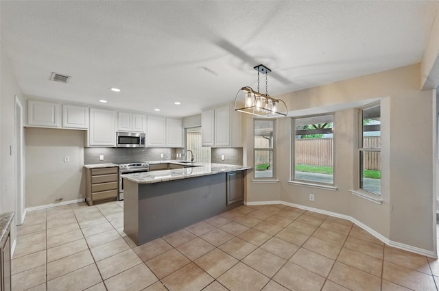 kitchen with a sink, stainless steel appliances, a peninsula, light tile patterned floors, and visible vents