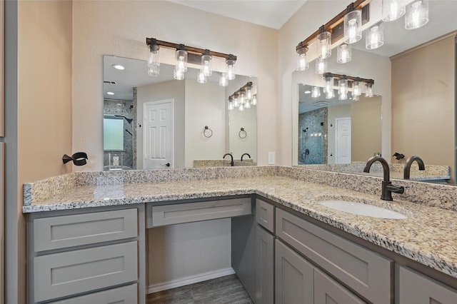 full bath featuring a sink, a shower stall, double vanity, and wood finished floors